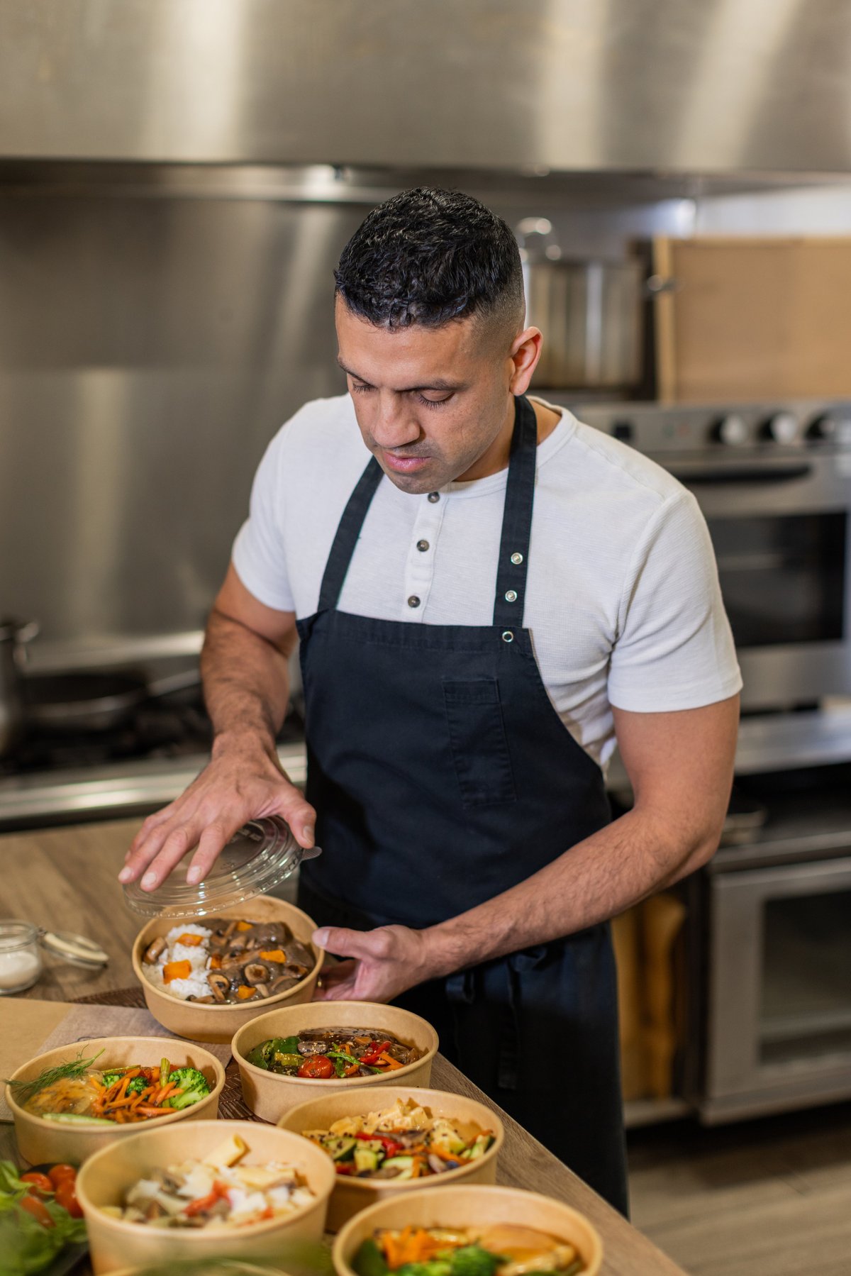 Chef packing fresh healthy meals into eco-friendly takeout bowls