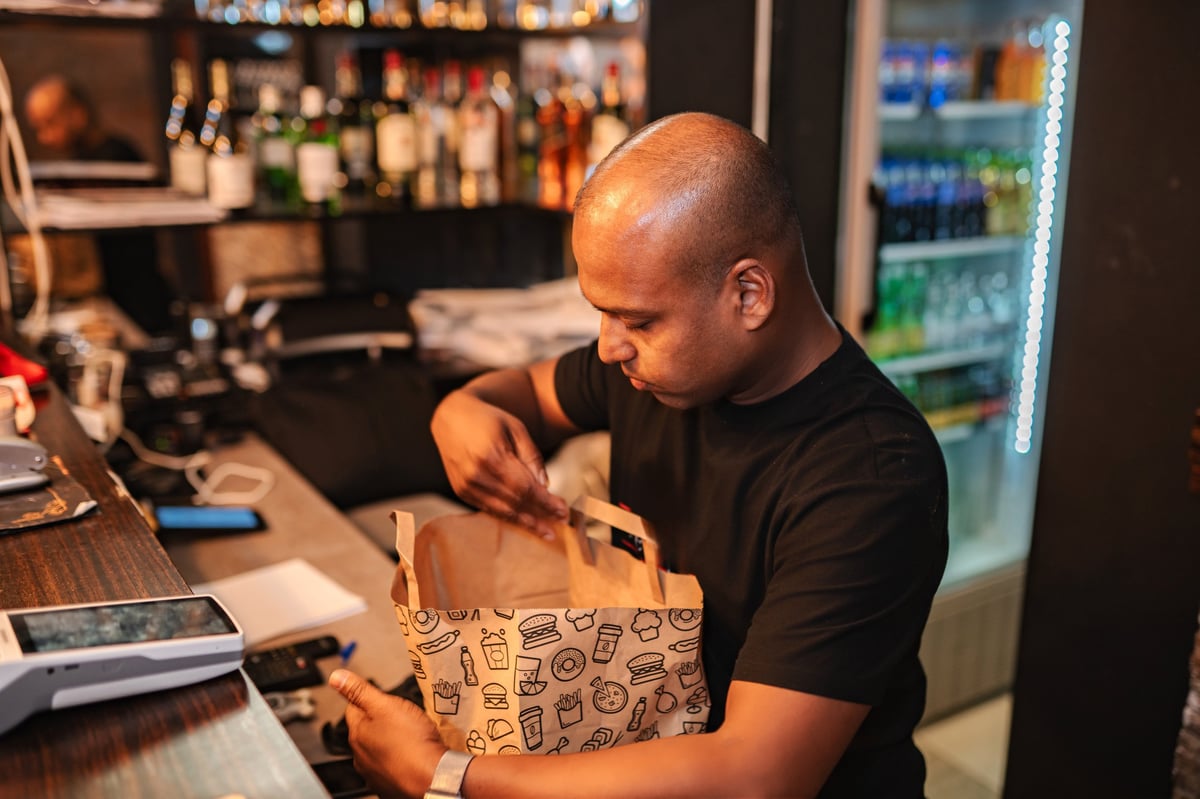PrepDrop team member packing a fresh meal into a delivery bag